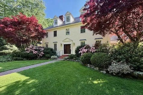Cream colonial home with a flowering front garden and lawn