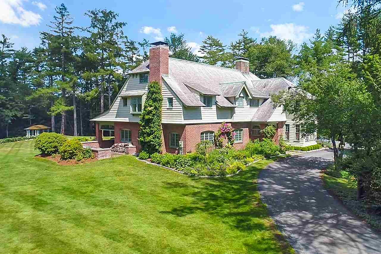 Shingle-style home with a brick chimney and a curving driveway