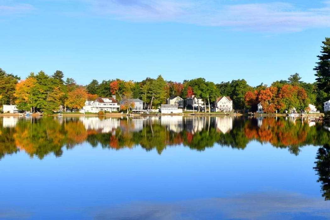 Lakefront homes in Salem NH reflected in still water in autumn